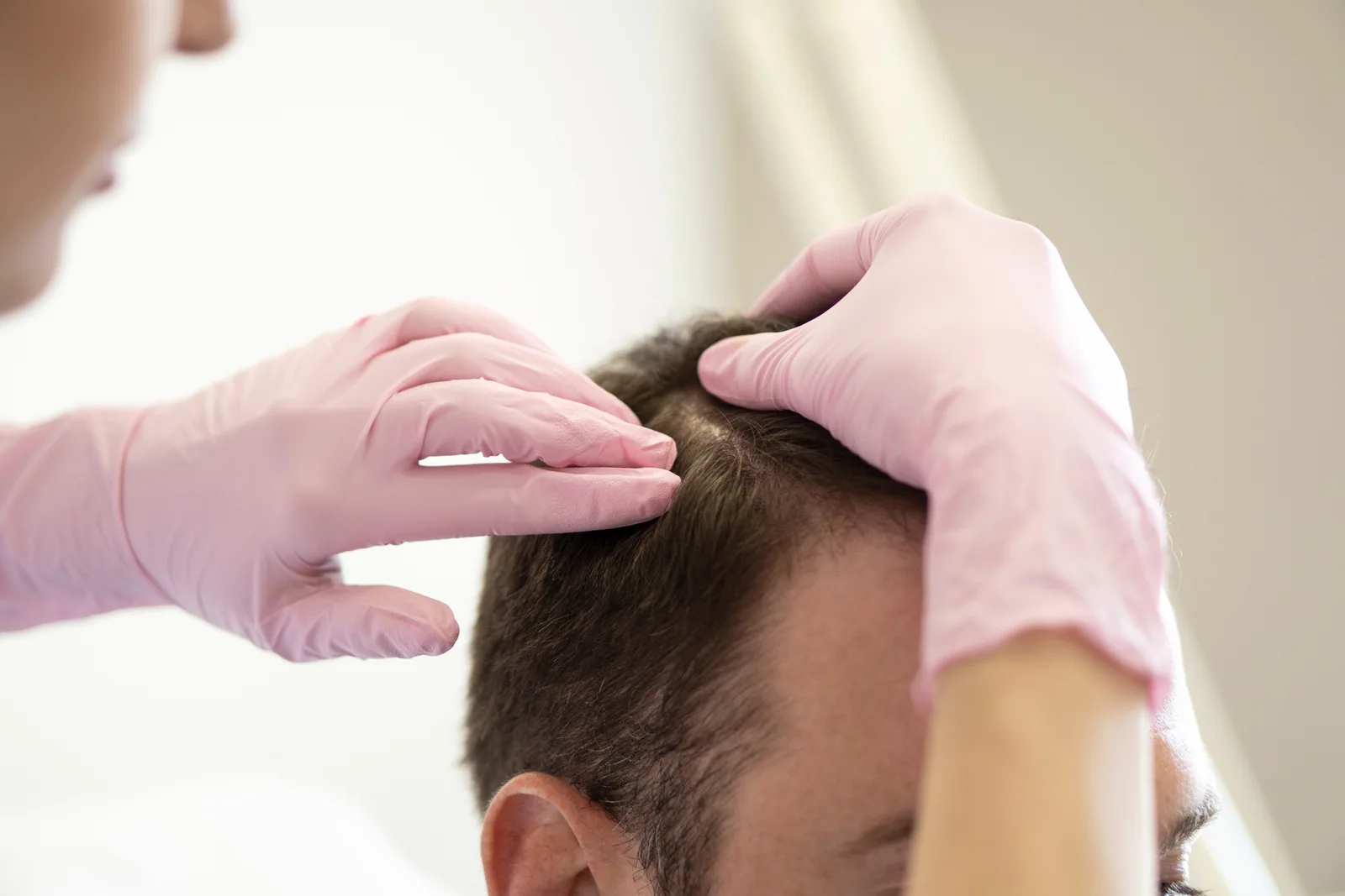 Gloved hands examining the scalp and hair